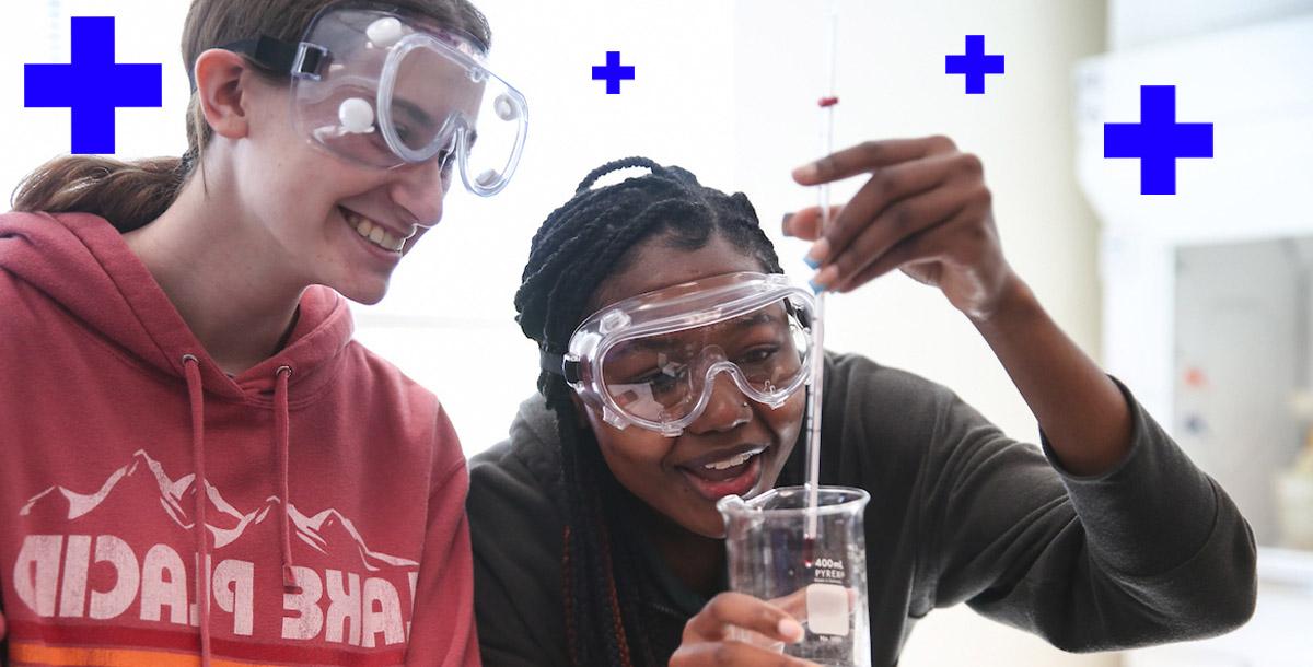 Two students wearing protective gear in a science lab.