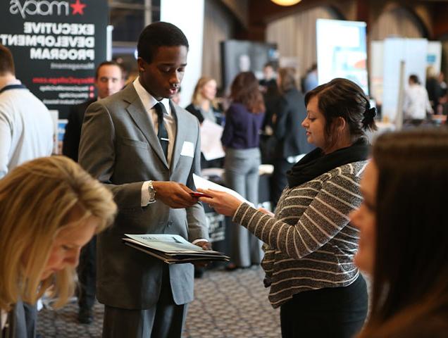 Entrepreneurship and Innovation major connecting with a professional at a career fair 